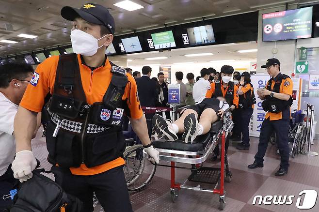 119구조대가 전국소년체육대회에 참가하기 위해 항공기에 탑승했던 초·중학생 제주특별자치도 선수단 가운데 대구공항 도착 직후 고통을 호소하는 선수들을 들것을 이용해 구급차로 옮기고 있다. 2023.5.26/뉴스1 ⓒ News1 공정식 기자