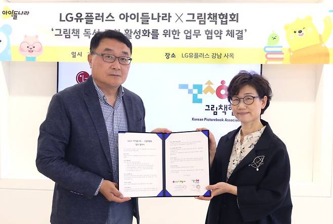 LG유플러스 박종욱 아이들나라CO(왼쪽)와 그림책협회 이영경 회장이 아이들나라 사옥에서 업무협약을 맺고 기념 사진을 촬영하고 있다. LG유플러스 제공