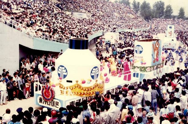 1980년대초 당시 울산의 대표축제인 공업축제 참가자들이 울산종합운동장에서 여러 기업체 상징 조형물을 앞세우고 퍼레이드를 벌이고 있다./울산시 제공