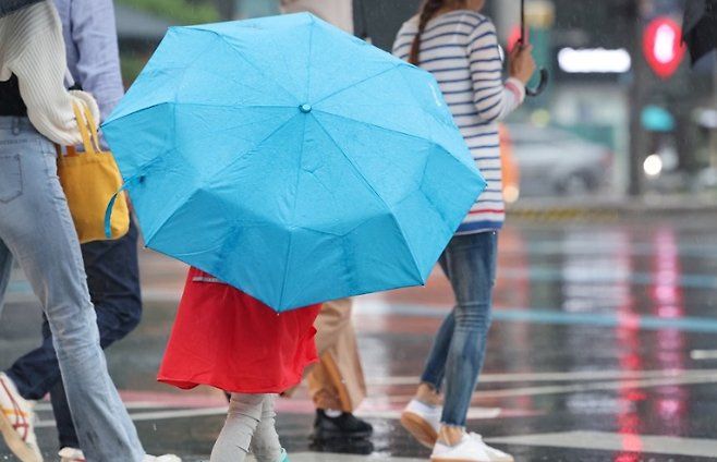 아이가 도심 한복판에서 우산을 쓰고 걸어가고 있다. / 사진=연합뉴스