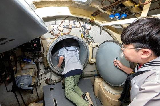 심예준(왼쪽) 학생기자가 잠수정 함수 내부 맨 앞에 있는 특수요원 수중 출입구 안을 확인하고 있다.