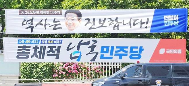 지난 23일 서울 여의도 국회 앞에 붙어 있는 여야 현수막. 더불어민주당이 노무현 전 대통령 14주기를 맞아 ‘역사는 진보합니다’란 현수막을 달자, 국민의힘은 아래에 ‘총체적 남국 민주당’이란 현수막을 설치했다. /박국희 기자