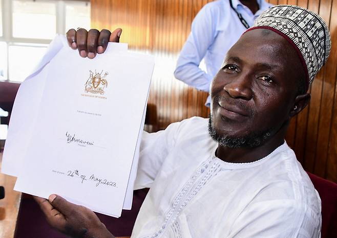 우간다 성소수자 차별 강화법을 대표 발의한 아수만 바살리르 의원이 29일(현지시간) 수도 캄팔라에서 기자회견을 열고 요웨리 무세베니 대통령이 서명한 법안을 들고 포즈를 취하고 있다. 로이터연합뉴스