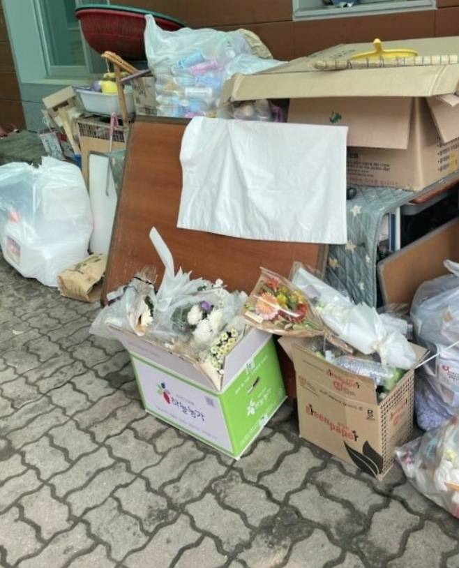 충남 천안시민들이 학교폭력 피해를 호소하고 사망한 고 김상연(18)군을 추모하고자 김군 모교에 가져다 놓은 꽃을 학교 측이 폐기했다는 의혹이 제기돼 논란이 일고 있다. 사진은 30일 오전쯤 박스에 담겨 쓰레기 봉투 옆으로 옮겨진 꽃다발. / 사진 = 온라인 커뮤니티 캡처