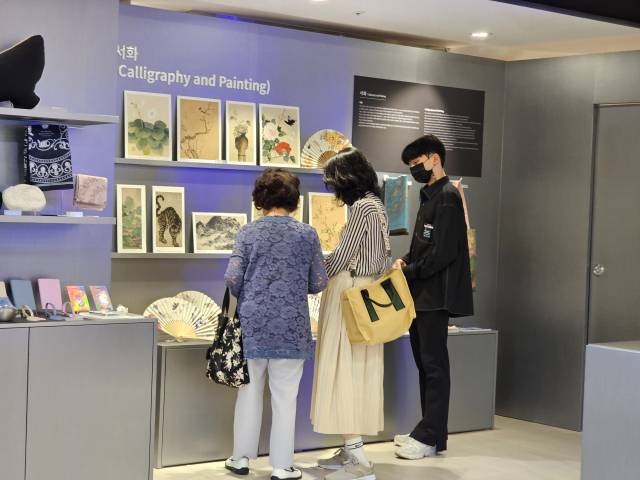 롯데백화점 서울 명동 본점에 문 연 국립중앙박물관 기념품 팝업 매장인 ‘나에게 온 보물, 뮷:즈(MU:DS : Museum Goods)’ 방문객이 매장 직원으로부터 제품 안내를 받고 있다. 이번 팝업 운영을 위해 국립중앙박물관 기념품 매장 담당자가 파견 와 직원들을 교육하고 있다./송주희기자