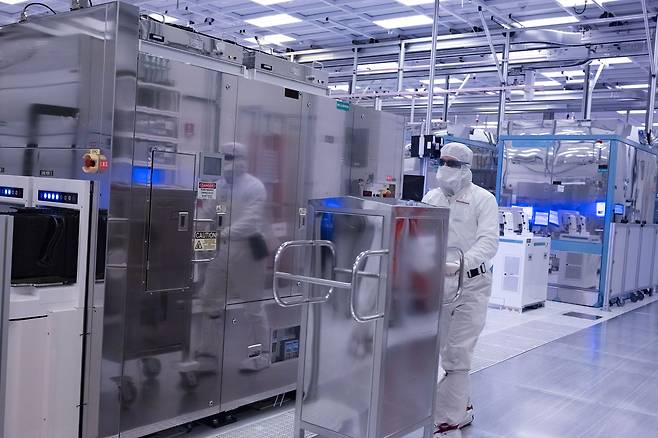 A photo from November 2021 shows employees in cleanroom "bunny suits" working at Intel's D1X factory in Hillsboro, Oregon. A D1X fab expansion due for completion in 2022 will help meet a sharply increasing global demand for semiconductors. Intel's chip-manufacturing operation in Oregon is the company's biggest site worldwide. The company's 21,000 employees in Oregon make Intel the state's single largest private employer. (Credit: Walden Kirsch/Intel Corporation)