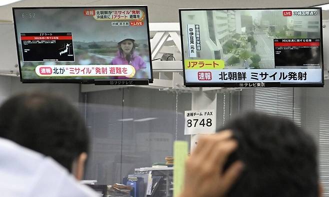 31일 일본 도쿄에서 주민들이 TV에 뜬 북한 미사일 관련 속보를 바라보고 있다. 이날 오전 일본 정부는 전국순시경보시스템(J-ALERT)을 통해 대피 명령을 내렸지만 약 30분 만에 해제했다. 도쿄/AP 연합뉴스