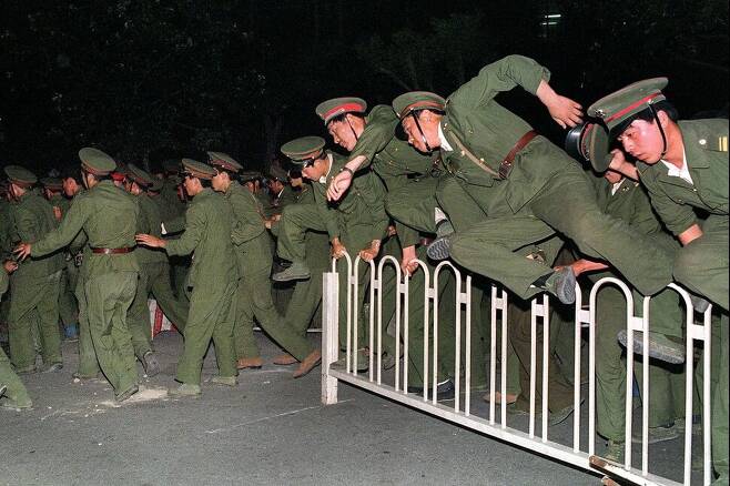 1989년 6월4일 밤 중국 인민해방군이 베이징 톈안먼 광장에서 민주화 시위대를 진압하기 위해 울타리를 뛰어넘고 있다. 2023년 6월 4일은 중국군이 베이징 톈안먼 광장 주변의 평화로운 민주화 시위대를 유혈 진압한 지 34주년이 되는 날이다. AFP 연합뉴스