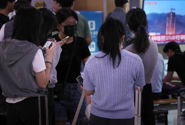 31일 오전 서울역 대합실 TV에 관련 뉴스속보가 나오는 가운데 수학여행을 떠나기 위해 모인 학생들이 갑작스럽게 울린 경보음을 듣고 휴대전화 위급재난문자를 확인하고 있다. 행안부는 "서울특별시에서 발령한 경계경보는 오발령"이라고 정정했다. / 사진=연합뉴스