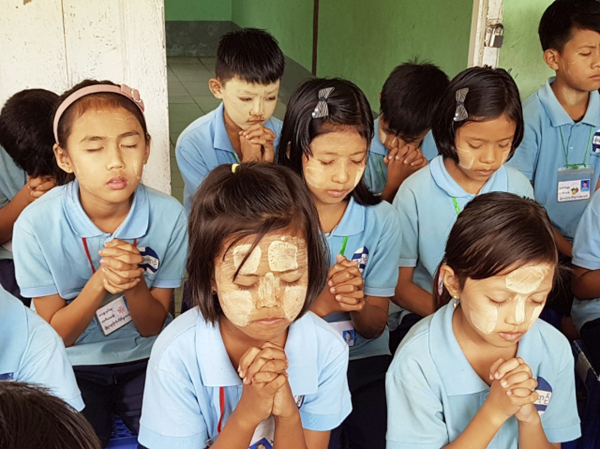 미얀마 양곤 새싹초등학교 학생들이 2020년 두 손을 모아 기도하고 있다. 아래는 손문수(왼쪽) 동탄순복음교회 목사가 2019년 8월 충남 서천 춘장대해수욕장에서 열린 침례식에서 한 남성 성도에게 침례를 베풀고 있는 모습. 국민일보DB