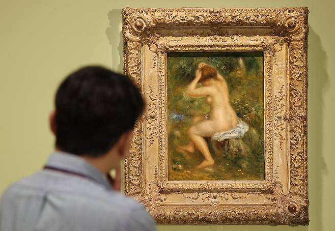 A reporter looks at the painting "A Bather," by Pierre-Auguste Renoir, on Thursday at the exhibition "Eyes on Us: Masterpieces from the National Gallery, London" at the National Museum of Korea. (Yonhap)