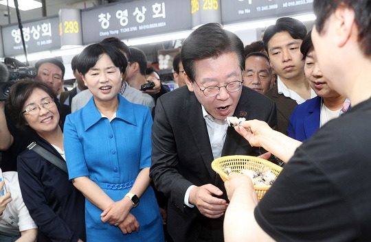 이재명 더불어민주당 대표가 3일 부산 중구 자갈치시장을 방문, 상인이 건네는 활전복회를 맛보고 있다. 사진=뉴시스