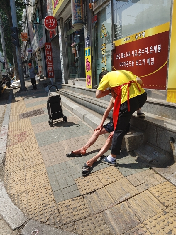 김유만 박달1동 주민자치위원회 부위원장(오른쪽)이 지난 4일 자신의 가게 앞 도로변에서 머리에 피를 흘리고 있는 50대 남성의 머리를 지혈하고 있는 모습. 박달1동 제공