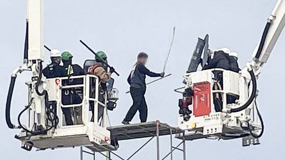 지난달 31일 오전 전남 광양시 포스코 광양제철소 인근 도로에서 높이 7ｍ 망루를 설치해 고공농성을 벌인 한국노총 금속노련 간부가 체포에 나선 경찰관에게 쇠파이프를 휘두르고 있다. 연합뉴스