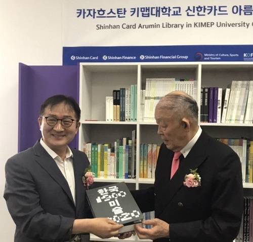 정길화 진흥원장(왼쪽)이 방찬영 키맵대학교 총장에게 한국문학도서를 전달하고 있다.