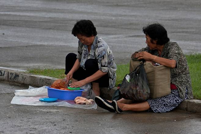 A street vendor checks her produce as a woman looks on in Pyongyang, North Korea (Photo Courtesy of Roman Harak)