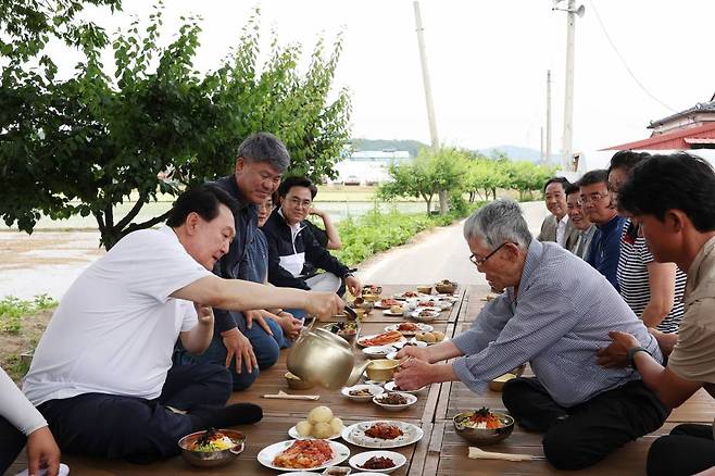 [서울=뉴시스] 윤석열 대통령이 7일 충남 부여군 임천면 꿈에영농조합법인을 방문해 모내기를 마친 뒤 주민들과 새참을 먹고 있다. (사진=대통령실 제공) 2023.06.07. *재판매 및 DB 금지