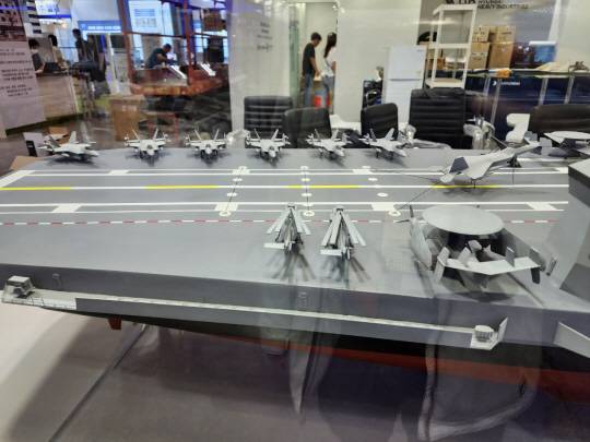 HD현대중공업이 7일 부산 벡스코에서 개막한 해양방위산업전(MADEX 2023) 자체 부스에서 경항모 대신 정규 항모로 대형화한 업그레이드된 한국형 항공모함 모형을 선보이고 있다. 한국항공우주산업(KAI)이 개발을 추진 중인 국산 함재기인 KF-21N(네이비)가 탑재됐고, 최신형 캐터펄트(사출기) 방식이 채택됐다. 오른쪽 우측에 최신 조기병보기 E-2D 호크아이도 눈에 띈다. 디펜스 타임즈 제공