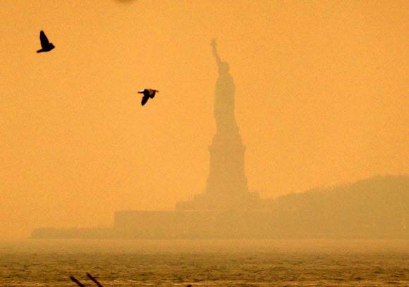 7일(현지시간) 캐나다 산불의 영향으로 미국 뉴욕의 하늘이 오렌지색으로 변한 가운데 자유의 여신상이 연기에 휩싸여 뿌옇게 보이고 있다. 2023.6.7 UPI 연합뉴스