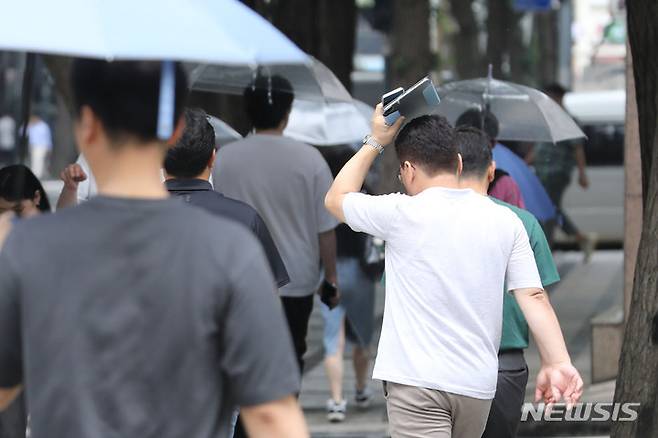 [서울=뉴시스] 권창회 기자 = 지난 8일 오후 서울 종로구 청계천 인근에서 한 시민이 소지품으로 비를 피하고 있다. 2023.06.08. kch0523@newsis.com