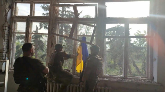 우크라이나군이 11일(현지 시간) 러시아가 점령했던 동부 도네츠크주 블라호다트네 마을의 한 건물 창문에 우크라이나 국기를 내걸고 있다. 이날 우크라이나는 대반격 작전 수행 후 격전지 마을 3곳을 탈환했다고 전했다. 로이터연합뉴스