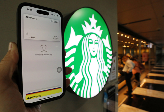A model demonstrates Apple Pay at a Starbucks store in Seoul on May 8. [NEWS1]