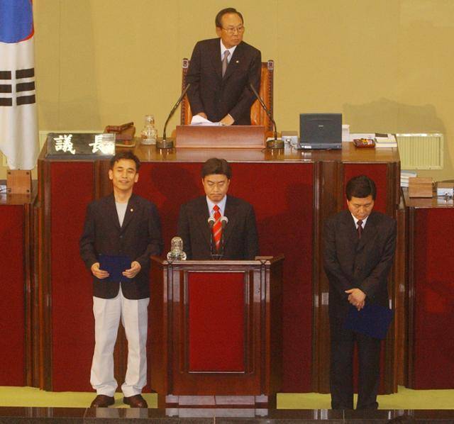 2003년 4월 29일 서울 여의도 국회 본회의장에서 유시민(왼쪽) 국민개혁정당 의원이 흰색 면바지 차림으로 의원선서를 하기 위해 단상에 서 있다. 한국일보 자료사진