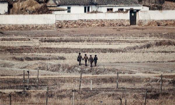 인천 강화군 접경지역에서 바라본 북한 개풍군 모습으로, 군인으로 추정되는 사람들이 손을 잡은 채 나란히 걷고 있다. 세계일보 자료사진