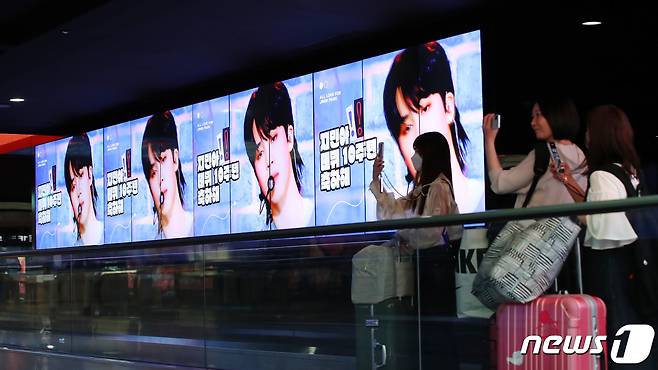 15일 인천국제공항 1터미널 아트미디어터널에서 외국인관광객이 방탄소년단(BTS) 데뷔 10주년 축하 영상을 스마트폰에 담고 있다. ⓒ News1