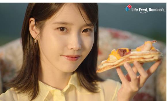 도미노피자의 광고모델인 가수 아이유가 피자를 들고 있는 모습. [사진=도미노피자]