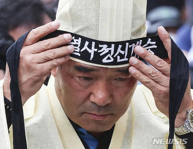 [서울=뉴시스] 김근수 기자 = 건설노조 故 양회동씨의 장례절차가 시작된 17일 서울 중구 세종대로 인근에서 열린  故 양회동 열사 범국민 추모대회에서 장옥기 건설노조 위원장이 머리띠를 묶고 있다. 2023.06.17. ks@newsis.com