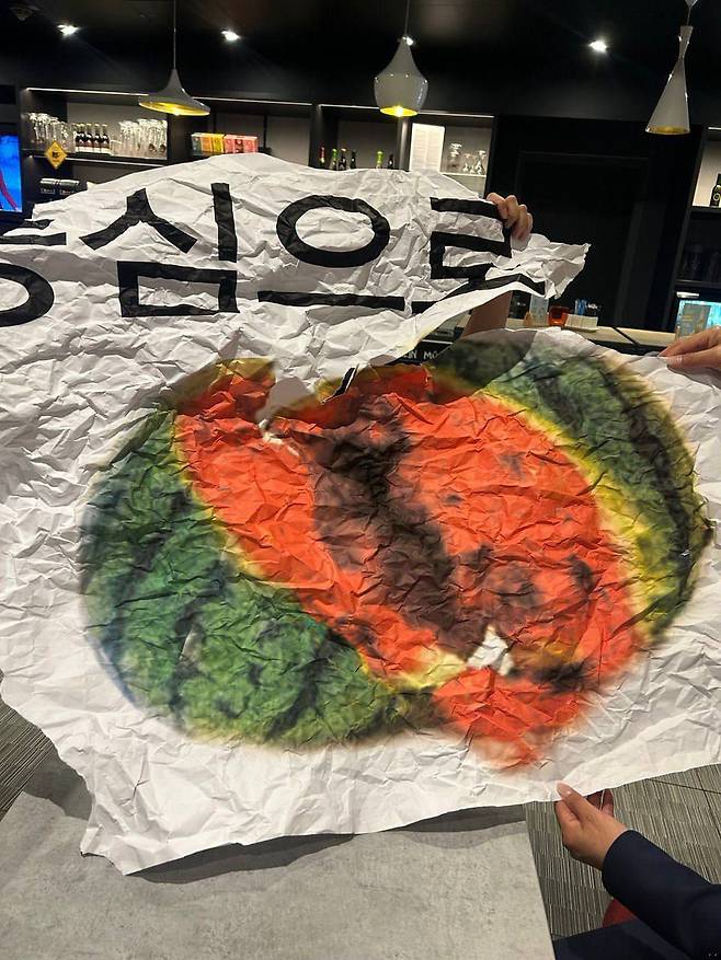 지난 12일(현지 시각) 이재명 대표 강성 지지자들이 이낙연 전 대표의 독일 강연에 들고 온 현수막. 깨진 수박 그림 위에 '이재명 당 대표를 중심으로'라는 글귀가 적혀있다. /독자 제공