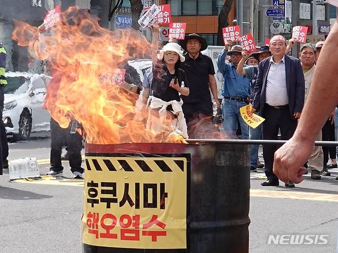 [제주=뉴시스] 오영재 기자 = 제주 농·어민들이 지난 13일 오후 제주시 노형오거리 앞에서 열린 '핵 오염수 해양 투기 저지를 위한 제주범도민대회'에서 욱일기를 태우고 있다. 2023.06.13. oyj4343@newsis.com