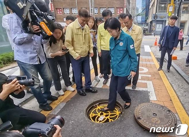 한화진 환경부 장관이 23일 서울 강남역 인근의 맨홀추락방지시설 위에 올라가고 있다. 한 장관과 전성수 서초구청장, 서울시 관계자 등은 이날 오전 서울 서초구 강남역 일대에서 장마철을 앞두고 빗물받이 청소 상태 등 침수 해소 사업 진척 상황을 살폈다. 2023.6.23/뉴스1 ⓒ News1 황덕현 기후환경전문기자