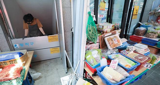 본격적인 장마를 앞둔 23일 서울 동작구 남성사계시장에서 한 상인이 폭우에 대비해 건물 입구에 물막이판을 설치해보고 있다.  이 시장은 지난해 8월 집중호우로 점포 130여 곳의 절반에 가까운 50여 곳이 침수되는 등 큰 피해를 보았다. 성동훈 기자