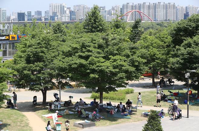 서울 영등포구 여의도 한강시민공원에서  시민들이 나무 그늘에 앉아 더위를 식히고 있다. /뉴스1