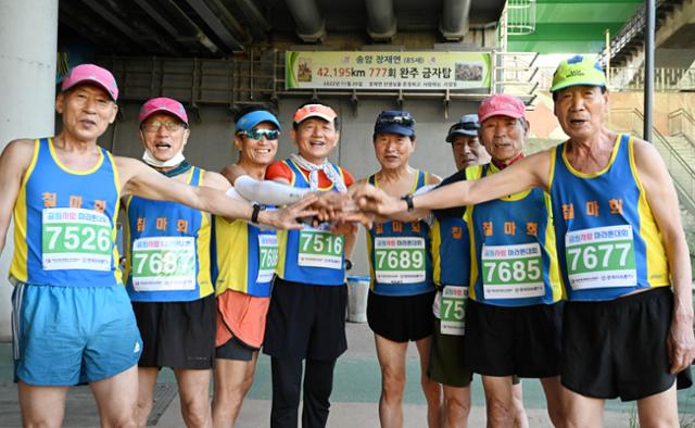 시니어 마라톤 동호회 '칠마회' 회원들이 3일 서울 도림천변에서 열린 공원사랑마라톤대회에 참가해 파이팅을 외치고 있다. 뒤쪽으로 장재연 회장의 777회 완주 축하 현수막이 걸려있다. (왼쪽부터) 정진우 김용석 안희규 육용국 이우찬 이범재 장재연 최남수씨. 왕태석 선임기자