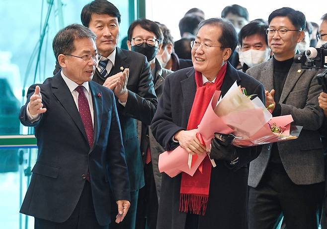 지난해 12월 홍준표 대구시장이 경북 군위군청을 방문해 환영의 꽃다발을 받은 뒤 김진열 군위군수와 회의실로 향하고 있다./뉴스1