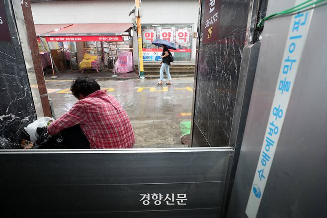 수도권 대부분 지역에 호우주의보가 발령된 29일 지난해 폭우로 침수 피해가 발생한 서울 동작구 남성사계시장 인근 건물에 설치된 물막이판 옆에서 한 노점상인이 비를 피하고 있다.