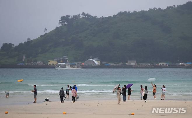 [제주=뉴시스] 우장호 기자 = 제주도 전역에 호우주의보가 내려진 30일 오후 제주시 한림읍 협재해수욕장을 찾은 관광객들이 궂은 날씨에도 해변을 거닐며 즐거운 시간을 보내고 있다. 기상청에 따르면 정체전선상에서 발달하는 저기압 영향으로 7월1일 오전까지 제주지역에 비가 내리겠다. 2023.06.30. woo1223@newsis.com