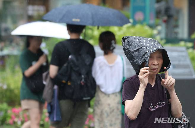 [서울=뉴시스] 황준선 기자 = 4일 오후 서울 종로구 세종대로 사거리에서 한 시민이 비닐봉지로 비를 피하고 있다. 2023.07.04. hwang@newsis.com