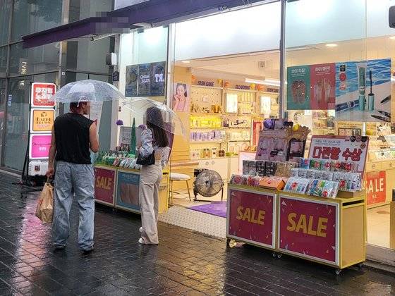 4일 오후 서울 중구 명동의 한 화장품 가게 앞으로 관광객들이 지나가고 있다. 가게의 자동문은 열린 상태로 고정돼 있고, 출입구 쪽에는 냉기를 바깥으로 보내기 위해 선풍기가 놓였다. 서지원 기자