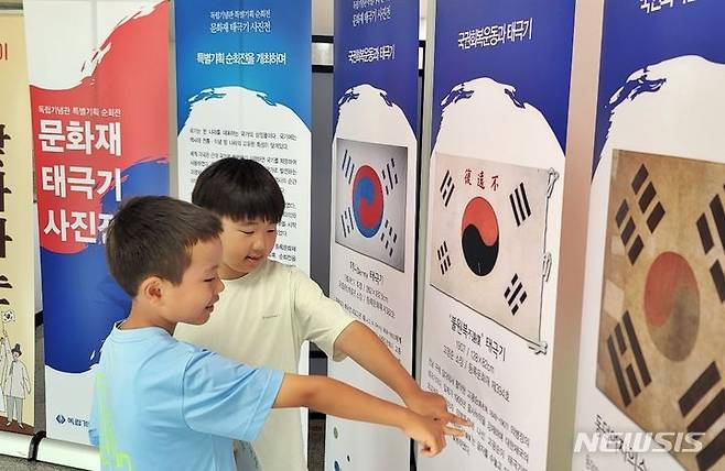 [제천=뉴시스] 이도근 기자= 충북 제천 동명초 어린이들이 6일 학교 1층 로비에서 열리고 있는 '문화재태극기 사진전'에서 태극기 문화재 등의 작품을 둘러보고 있다. 이번 사진전은 독립기념관 특별기획 순회전의 일환으로 오는 19일까지 이어진다. (사진=제천교육지원청 제공) 2023.7.6. photo@newsis.com *재판매 및 DB 금지