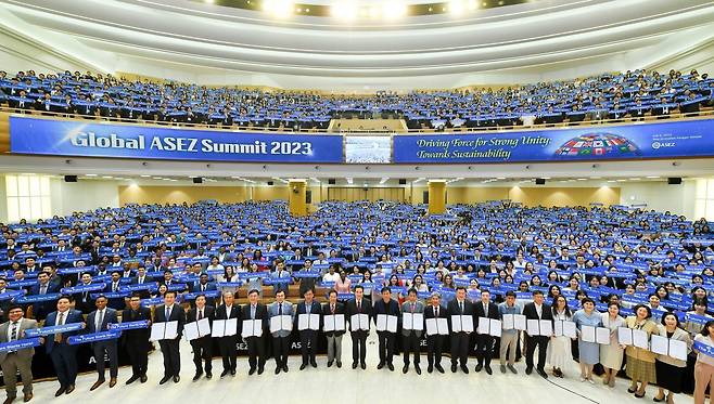 6일 경기 분당에 위치한 새예루살렘 판교성전에서 하나님의 교회 대학생봉사단 ASEZ가 ‘2023 전 세계 ASEZ 정상회의’를 개최했다. 하나님의 교회 총회장 김주철 목사와 박종길 전 문화체육부 차관을 비롯한 내·외빈들이 ‘U500 공동선언문’을 들고 있다. 뒤에는 40개국 약 500개 대학 1500여 명의 참석자들이 ‘The Future Starts here!(미래는 여기서 시작한다)’는 손 배너를 펼치며 환하게 웃고 있다.