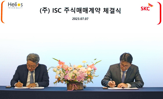 SKC CEO Park Won-cheol, right, signs an agreement with Jeon Je-mo, head of Helios Private Equity, Friday in central Seoul. [SKC]