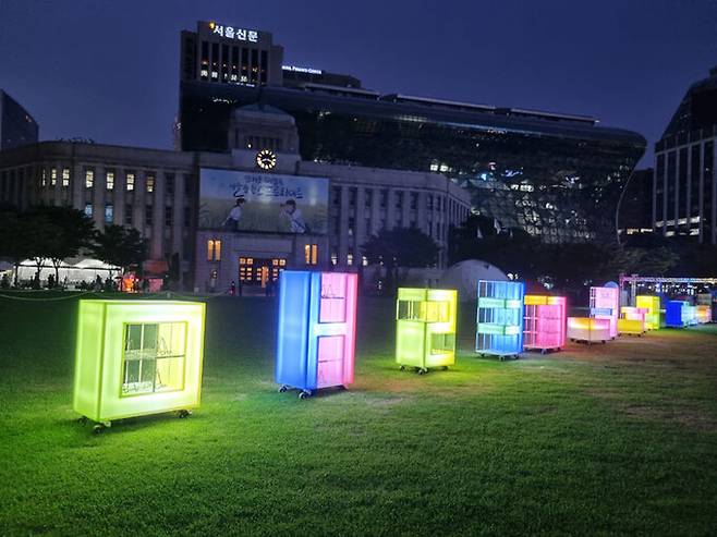 한여름&nbsp;밤 서울광장 풀밭 위에서&nbsp;독서를 즐길 수 있는 ‘밤의 여행 도서관’의 LED 빛&nbsp;서가. 서울도서관 제공&nbsp;