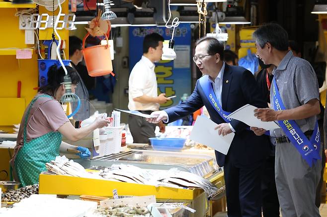 국제원자력기구(IAEA)가 후쿠시마 오염수 해양 방류 계획에 대해 국제 안전기준에 부합한다고 평가한 보고서를 내놓은 지 이틀째인 6일 오후 조승환 해수부장관이 인천 중구 인천종합어시장을 방문해 상인에게 수산물 안전 관련 안내문을 건네고 있다. /연합뉴스