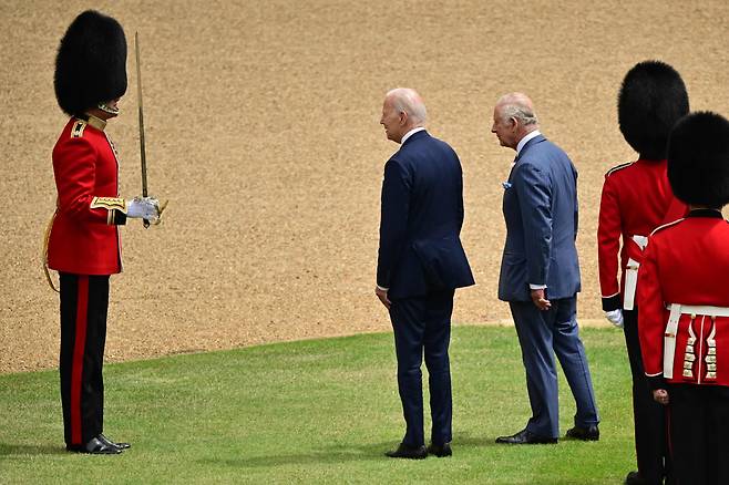 10일(현지 시간) 영국 런던 윈저성을 방문한 조 바이든 미국 대통령이 환영식 도중 한 근위병에게 말을 걸고 있다. 오른쪽은 찰스 3세 영국 국왕./AFP 연합뉴스