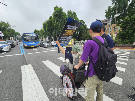 박경석 전장연 상임공동대표가 13일 오전 서울 종로구 마로니에 공원 앞 차도에서 시내버스 운행을 막는 기습 시위를 벌이고 있다.(사진=이영민 기자)