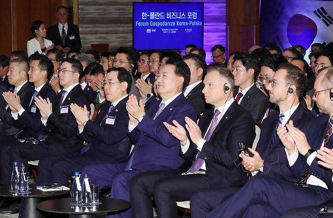 윤석열 대통령이 14일(현지 시각) 폴란드 바르샤바의 한 호텔에서 열린 한·폴란드 비즈니스 포럼에 참석해 박수를 치고 있다. 앞줄 왼쪽부터 구자은 LS그룹 회장, 김동관 한화 부회장, 구광모 LG 회장, 이창양 산업부 장관, 윤 대통령, 안제이 두다 폴란드 대통령./뉴시스